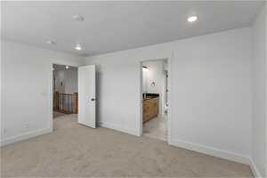 Unfurnished bedroom with light colored carpet and connected bathroom