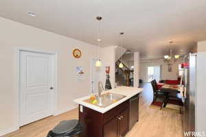 Kitchen with sink, a chandelier, light hardwood / wood-style floors, hanging light fixtures, and stainless steel appliances