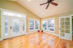 Unfurnished sunroom featuring vaulted ceiling, a healthy amount of sunlight, and ceiling fan