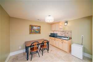Kitchen with sink, light brown cabinetry, tasteful backsplash, refrigerator, and light tile floors
