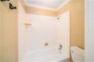 Bathroom with toilet, tub / shower combination, and crown molding