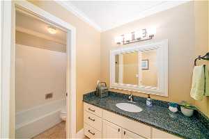 Full bathroom with toilet, ornamental molding, tile floors, oversized vanity, and bathing tub / shower combination