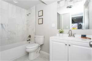 Full bathroom featuring vanity, toilet, tile floors, and tiled shower / bath