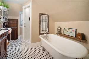 Bathroom featuring vanity, vaulted ceiling, a washtub, and a textured ceiling