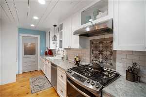 Kitchen with white cabinetry, tasteful backsplash, stainless steel appliances, and light hardwood / wood-style floors