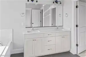 Bathroom with tile floors, double sink vanity, and a bath