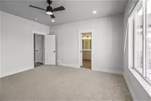 Unfurnished bedroom featuring connected bathroom, light colored carpet, and ceiling fan