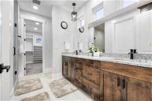 Bathroom with tile flooring, large vanity, double sink, and walk in shower