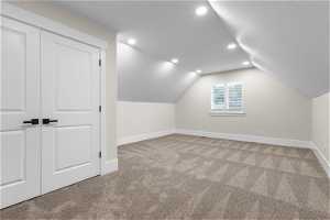 Additional living space featuring vaulted ceiling and light carpet