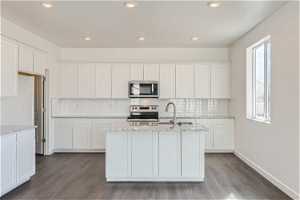 Kitchen featuring white cabinets, plenty of natural light, hardwood / wood-style flooring, and stainless steel appliances