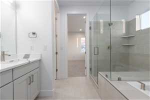 Bathroom featuring walk in shower, large vanity, and tile floors