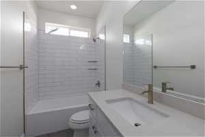 Full bathroom featuring tile flooring, vanity with extensive cabinet space, tiled shower / bath combo, and toilet