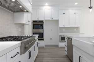 Kitchen featuring appliances with stainless steel finishes, pendant lighting, tasteful backsplash, and custom range hood