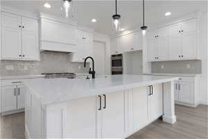 Kitchen with light wood-type flooring, decorative light fixtures, and backsplash