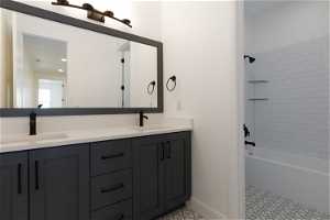 Bathroom featuring double vanity, tile flooring, and tiled shower / bath