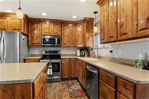 Kitchen with sink, decorative light fixtures, dark hardwood / wood-style floors, and stainless steel appliances