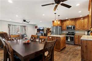 Kitchen with a center island, pendant lighting, dark wood-type flooring, stainless steel appliances, and ceiling fan