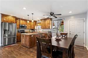 Kitchen featuring stainless steel appliances, ceiling fan, dark hardwood / wood-style flooring, pendant lighting, and a center island