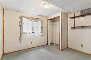 Unfurnished bedroom featuring light colored carpet, a closet, and a drop ceiling