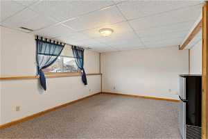 Empty room featuring light colored carpet and a drop ceiling