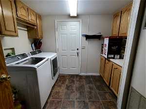 Washroom featuring a textured ceiling, cabinets, washer and clothes dryer, dark tile floors, and washer hookup
