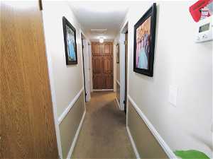 Hallway featuring crown molding and dark colored carpet
