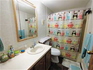 Bathroom featuring tile floors, toilet, tile walls, and oversized vanity