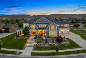 View of front of property with concrete driveway, a mountain view, a front lawn, french doors, and stone siding