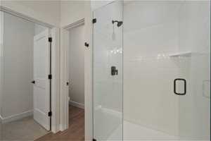 Bathroom with a shower with shower door, hardwood / wood-style flooring, and toilet