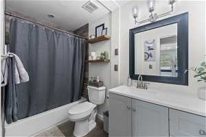 Full bathroom featuring shower / bathtub combination with curtain, vanity, toilet, and tile floors
