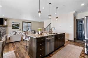 Kitchen featuring pendant lighting, an island with sink, dark hardwood / wood-style flooring, and dishwasher
