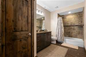 Full bathroom featuring shower / bathtub combination with curtain, vanity, toilet, and tile flooring