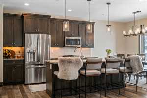 Kitchen featuring backsplash, stainless steel appliances, dark hardwood / wood-style flooring, and light stone countertops