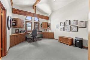 Home office with built in desk, light colored carpet, high vaulted ceiling, and beam ceiling