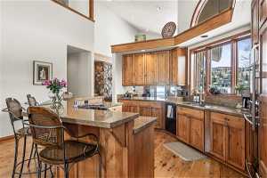 Kitchen featuring light hardwood / wood-style flooring, a breakfast bar, sink, and high vaulted ceiling