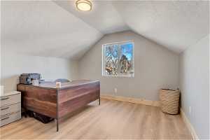 ADU Bedroom featuring light hardwood / wood-style flooring, a textured ceiling, and vaulted ceiling
