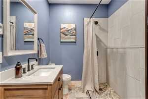 ADU Bathroom with tile flooring, curtained shower, large vanity, and toilet