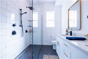 Master Bathroom with tiled shower, oversized vanity, toilet, and tile floors
