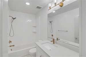 Full bathroom with tile flooring, large vanity, toilet, and washtub / shower combination