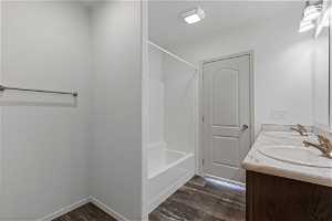 Bathroom featuring dual bowl vanity, tub / shower combination, and hardwood / wood-style floors