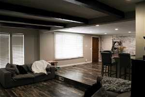 Living room with beam ceiling and dark wood-type flooring