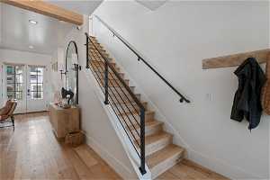 Stairs featuring light hardwood / wood-style flooring, french doors, and beamed ceiling