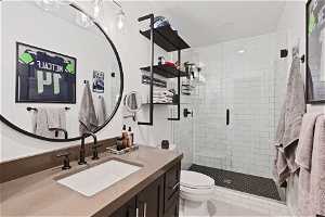 Bathroom featuring a shower with glass door, tile floors, toilet, and vanity