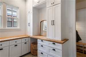 Laundry white cabinetry, butcher block countertops, and dark tile floors