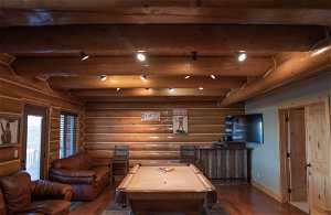 Interior space with dark wood-type flooring, beam ceiling, log walls, and pool table