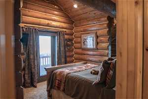 Carpeted bedroom featuring lofted ceiling, log walls, and wooden ceiling