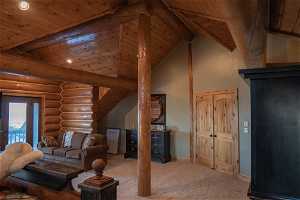 Master bedroom with high vaulted ceiling, wooden ceiling, beam ceiling, carpet, and rustic walls