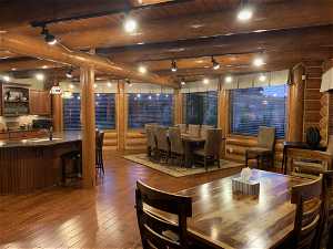 Dining room featuring dark hardwood / wood-style flooring, rustic walls, wood ceiling, and beamed ceiling