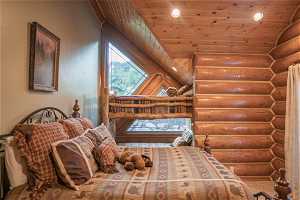 Bedroom with lofted ceiling, log walls, and wooden ceiling