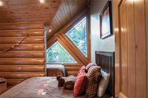 Bedroom with lofted ceiling, wood ceiling, and rustic walls